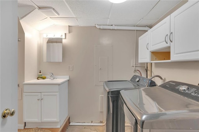 clothes washing area featuring cabinets, electric panel, sink, and washer and clothes dryer