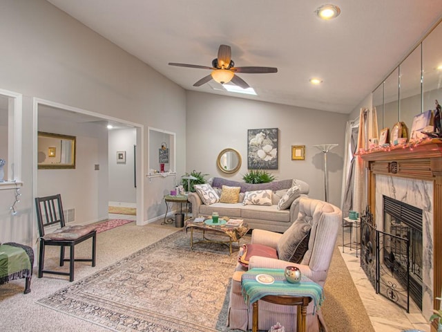 carpeted living room with vaulted ceiling, a tiled fireplace, and ceiling fan