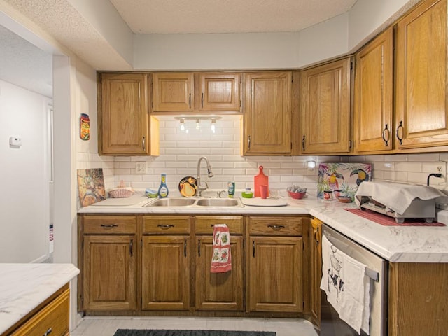 kitchen featuring stainless steel dishwasher, sink, a textured ceiling, and tasteful backsplash