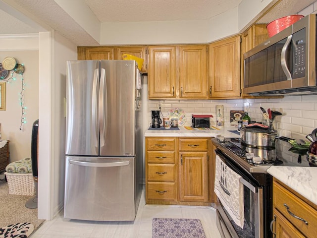 kitchen featuring tasteful backsplash, appliances with stainless steel finishes, light tile patterned floors, and a textured ceiling