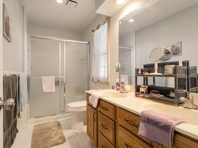 bathroom featuring vanity, a shower with shower door, and toilet