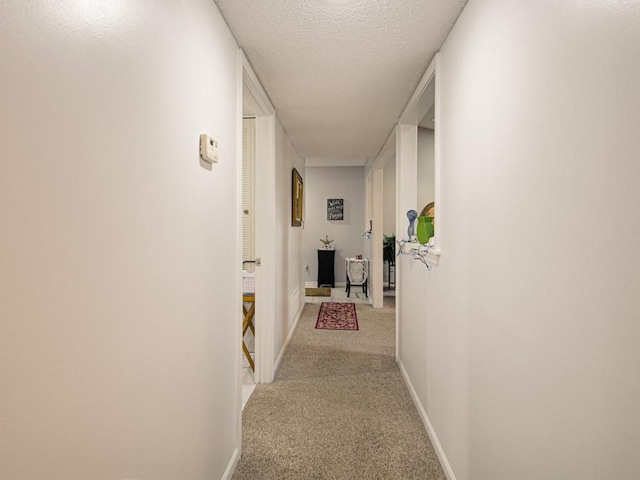 hall with a textured ceiling and carpet floors