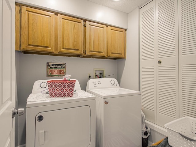 laundry room featuring cabinets, a textured ceiling, and washer and clothes dryer