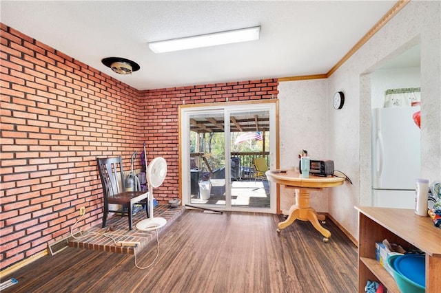 living area with crown molding, hardwood / wood-style floors, and brick wall