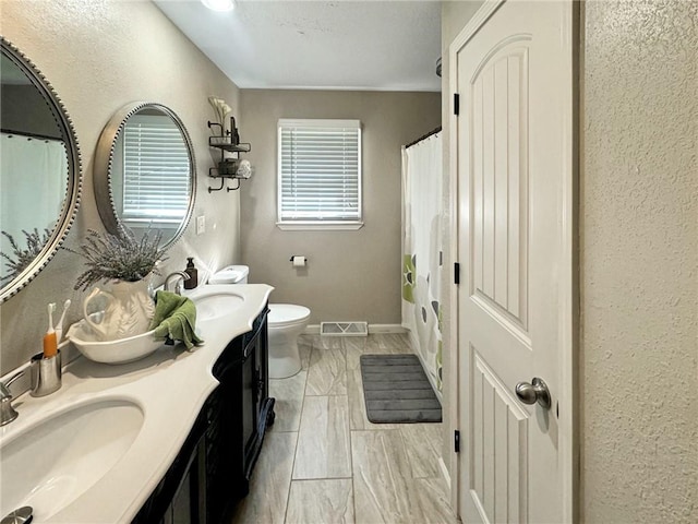 bathroom with curtained shower, vanity, and toilet