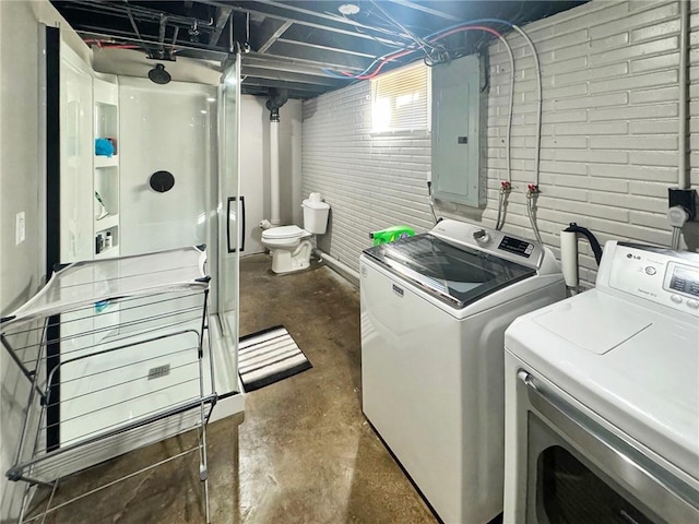 laundry room with electric panel, separate washer and dryer, and brick wall