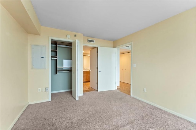 unfurnished bedroom with a closet, light carpet, and electric panel