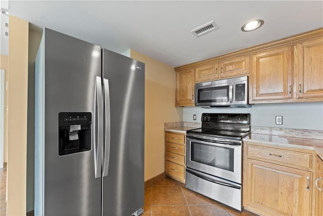 kitchen with light brown cabinetry, stainless steel appliances, and tile patterned floors