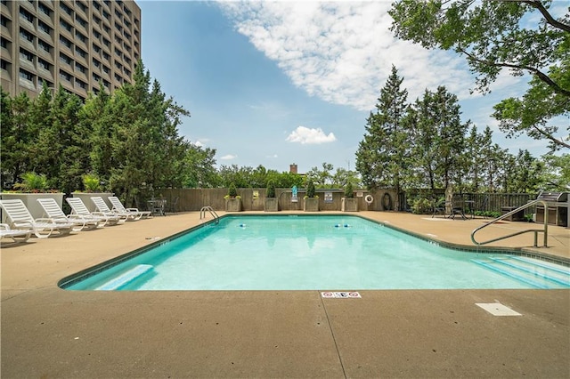 community pool with fence and a patio area