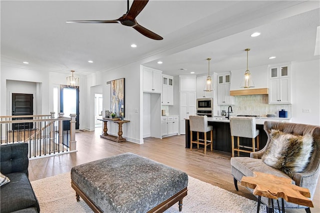 12967 S Constance St, Olathe, KS 66062 - living room featuring a ceiling fan, recessed lighting, ornamental molding, light wood finished floors, and a chandelier