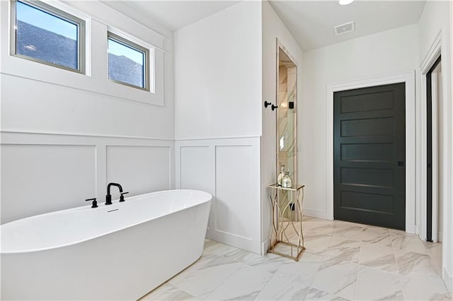 12967 S Constance St, Olathe, KS 66062 - bathroom with a decorative wall, marble look tiles, a freestanding bath, a tile shower, and a wainscoted wall