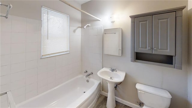 bathroom featuring toilet, tiled shower / bath combo, and hardwood / wood-style flooring