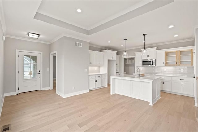 kitchen featuring white cabinets, an island with sink, and decorative light fixtures