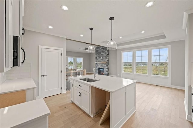 kitchen featuring a sink, a fireplace, light wood-type flooring, white cabinets, and recessed lighting
