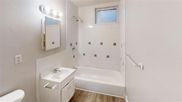 full bathroom with toilet, tiled shower / bath combo, hardwood / wood-style flooring, and vanity