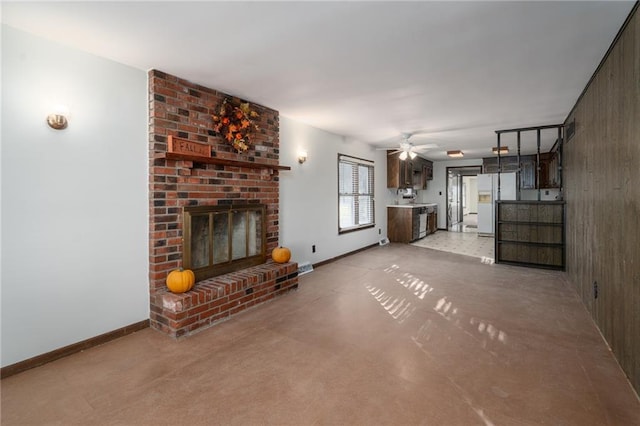 unfurnished living room with ceiling fan, wooden walls, and a brick fireplace