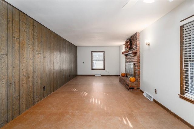 unfurnished living room with wooden walls and a fireplace