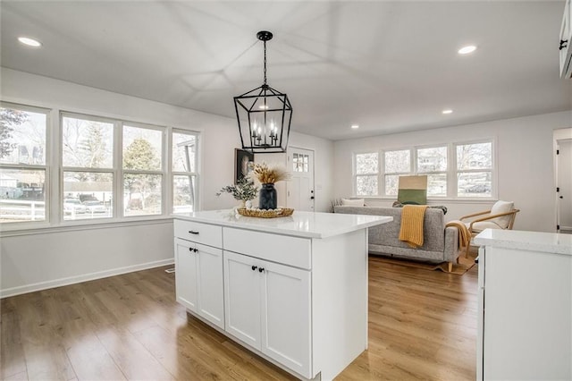 kitchen featuring white cabinets, decorative light fixtures, light hardwood / wood-style flooring, and plenty of natural light