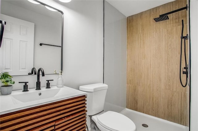 bathroom featuring vanity, toilet, and a tile shower