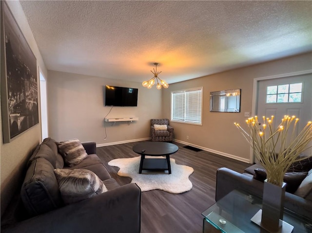 living room featuring a textured ceiling, an inviting chandelier, and dark hardwood / wood-style floors