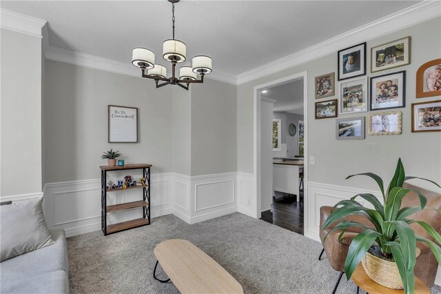 sitting room with ornamental molding, a chandelier, and carpet floors