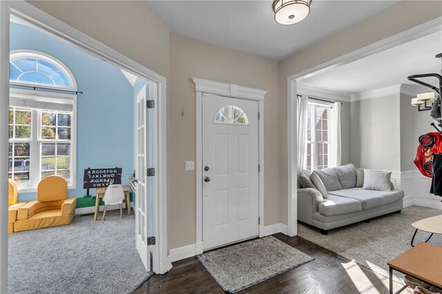 foyer featuring a healthy amount of sunlight, ornamental molding, and dark hardwood / wood-style floors