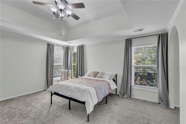 carpeted bedroom featuring multiple windows, ornamental molding, and ceiling fan