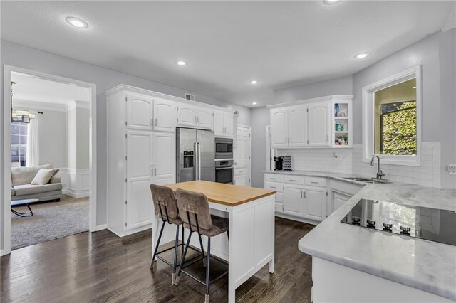 kitchen featuring appliances with stainless steel finishes, sink, a center island, dark hardwood / wood-style flooring, and white cabinetry