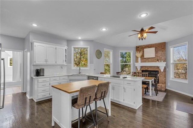 kitchen with white cabinets, ceiling fan, a kitchen island, dark wood-type flooring, and black electric stovetop