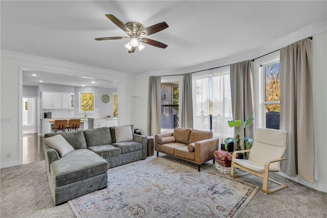 living room featuring light carpet, ornamental molding, and ceiling fan