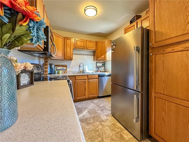 kitchen with backsplash, appliances with stainless steel finishes, and sink