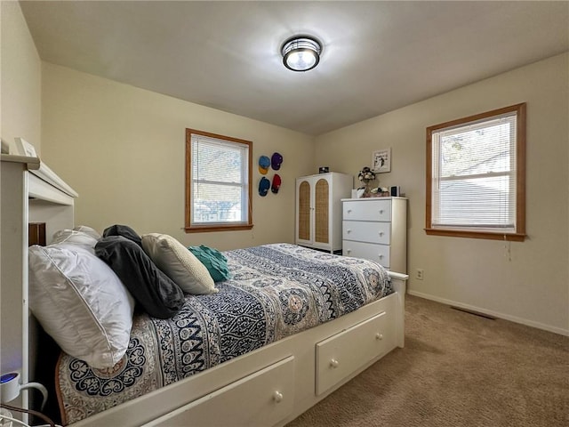 bedroom featuring light carpet and multiple windows