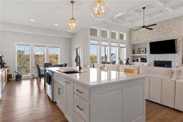 kitchen with white cabinets, dishwasher, sink, a kitchen island with sink, and coffered ceiling