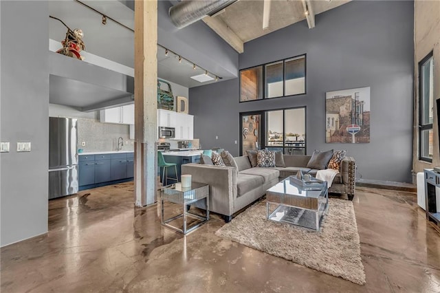 living room with sink, track lighting, and a high ceiling