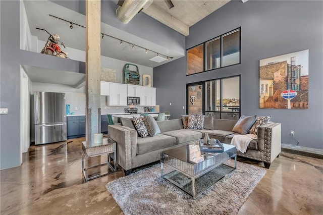 living room featuring track lighting, concrete floors, and a high ceiling