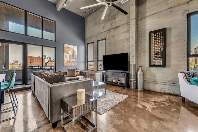 living room with ceiling fan, a towering ceiling, and concrete flooring