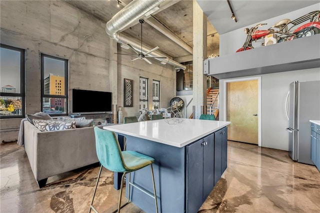 kitchen with blue cabinets, ceiling fan, a kitchen island, a breakfast bar area, and stainless steel refrigerator