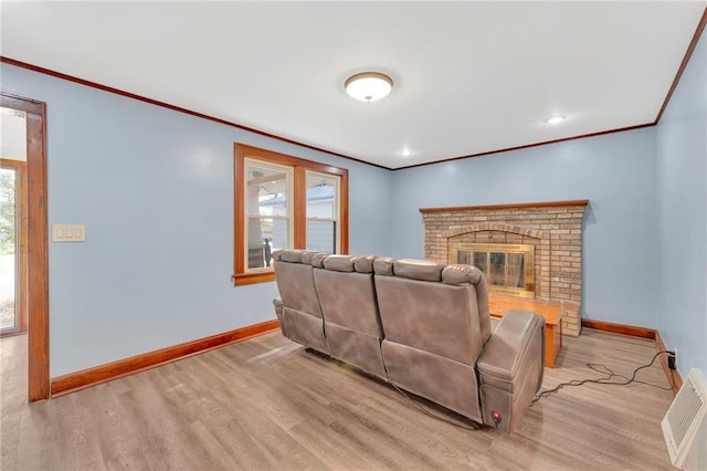 living room featuring a wealth of natural light, light hardwood / wood-style flooring, and a brick fireplace