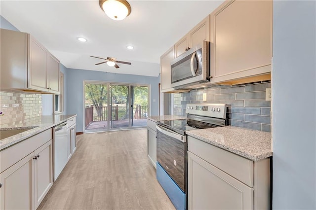 kitchen featuring decorative backsplash, light stone counters, stainless steel appliances, and light wood-type flooring