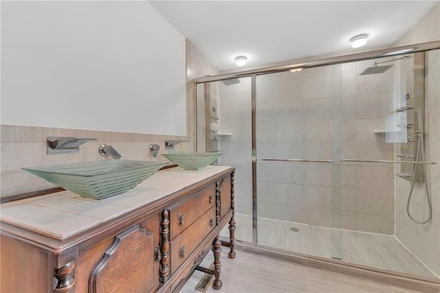 bathroom featuring vanity, tile walls, and a shower with shower door