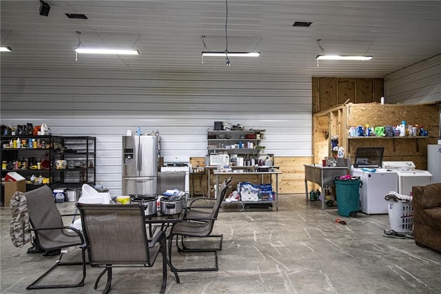 garage featuring wooden walls, stainless steel fridge with ice dispenser, and separate washer and dryer