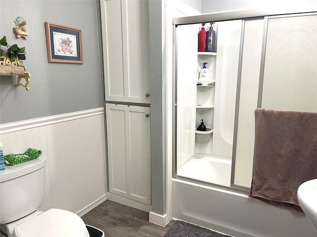 bathroom with toilet, enclosed tub / shower combo, and hardwood / wood-style floors