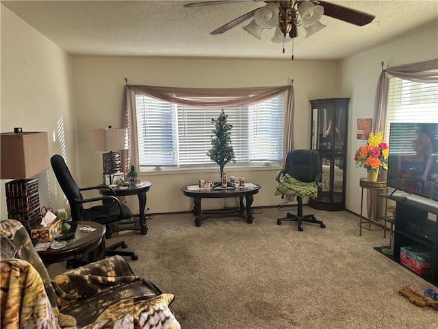 living area with ceiling fan, a textured ceiling, and carpet