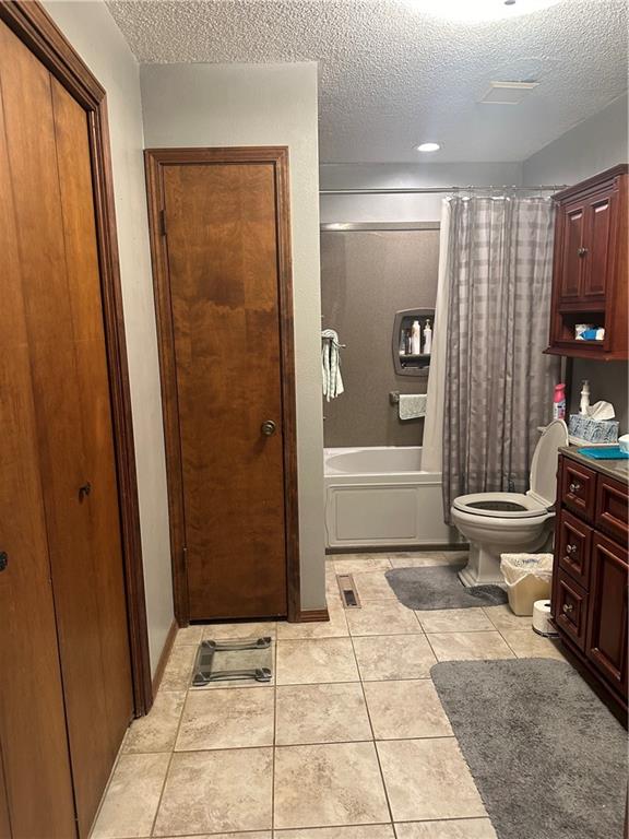 full bathroom with tile patterned flooring, vanity, a textured ceiling, and shower / tub combo