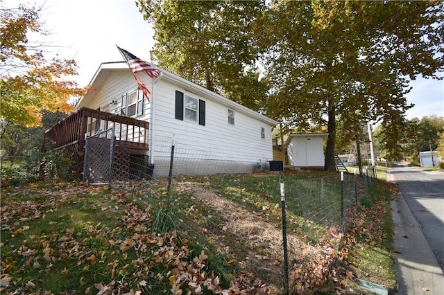 view of property exterior featuring central AC, a storage shed, and a deck