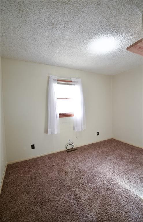 unfurnished room with a textured ceiling and carpet floors