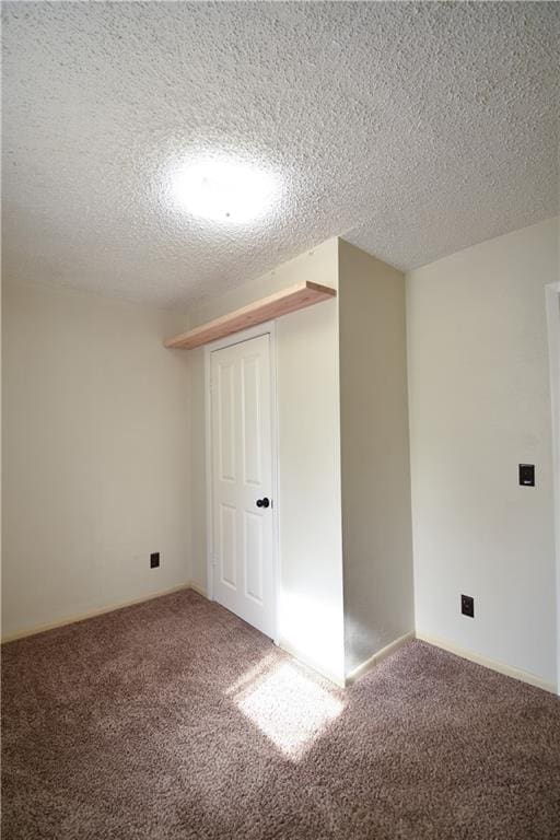 carpeted empty room featuring a textured ceiling