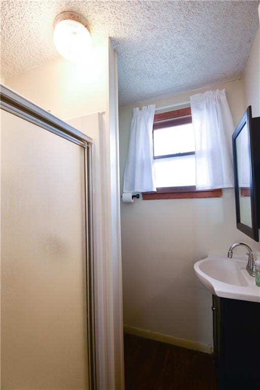 bathroom featuring vanity, walk in shower, and a textured ceiling