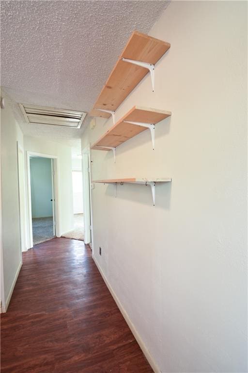 corridor featuring dark wood-type flooring and a textured ceiling