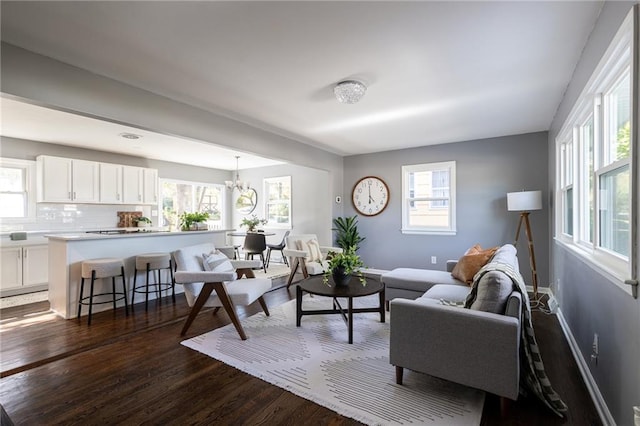 living room with a wealth of natural light, dark hardwood / wood-style floors, and a chandelier